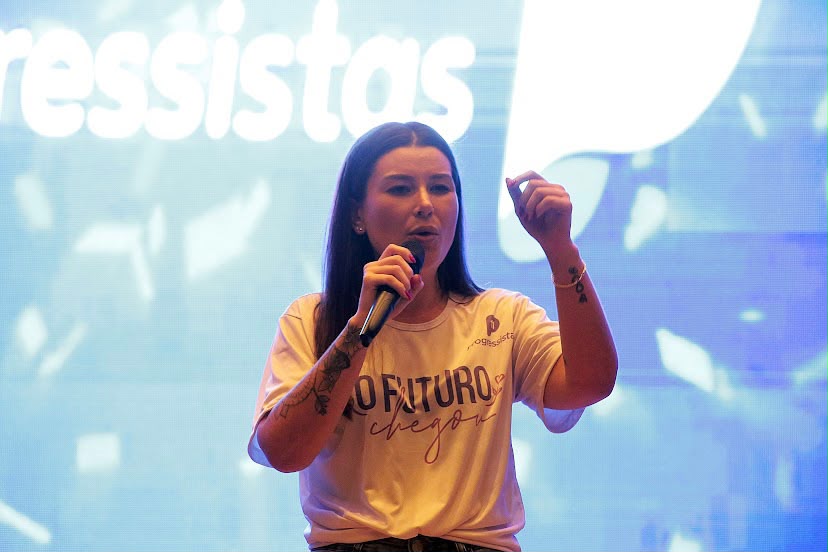 Joce Canto falando ao microfone em um evento